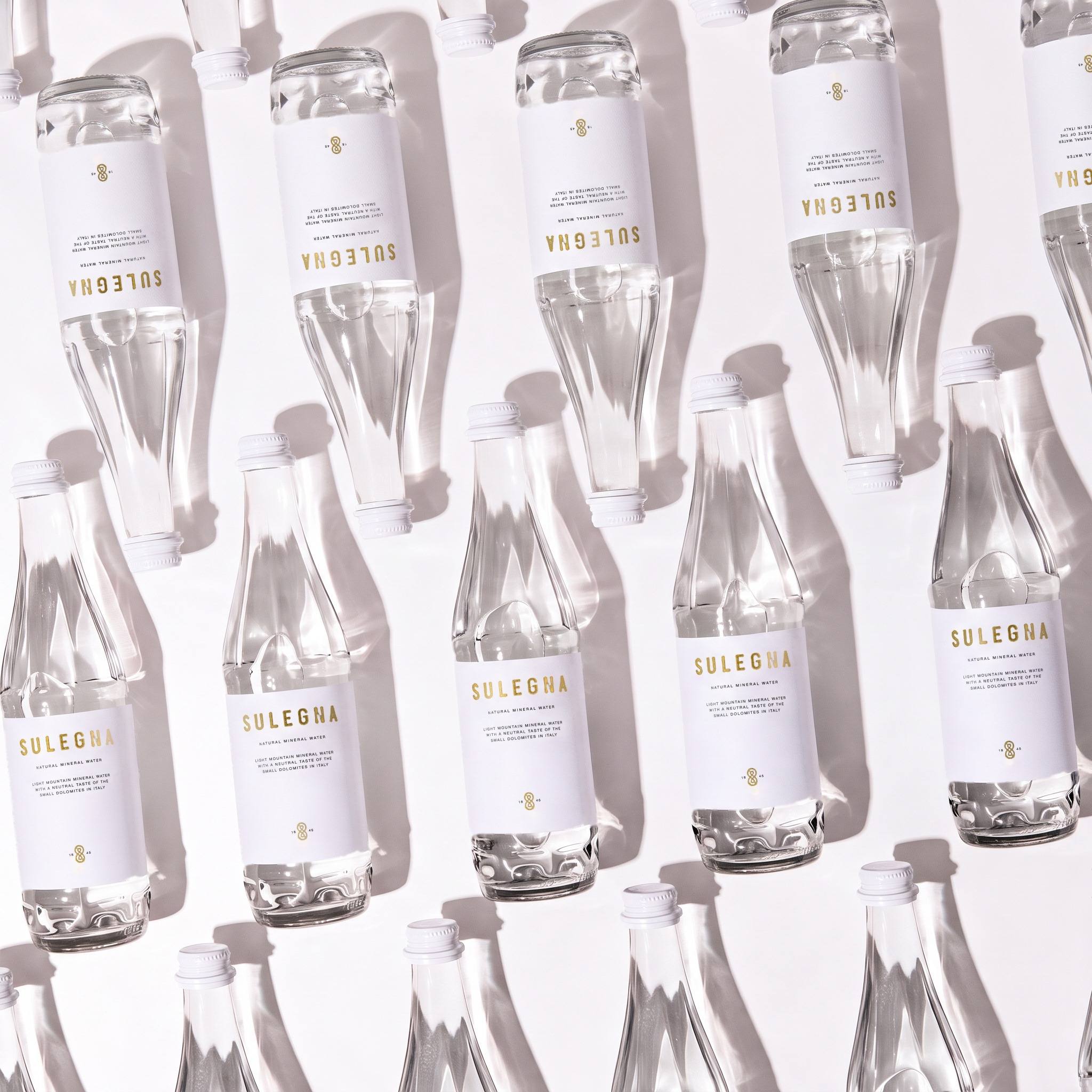 SULEGNA Natural bottles, 80 cl and 44 cl, standing together on a warm neutral background